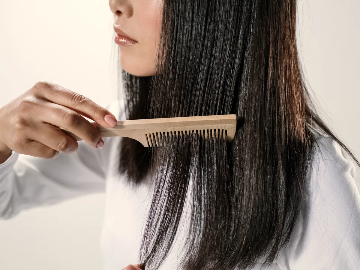 Peigne passé dans des cheveux longs et lisses