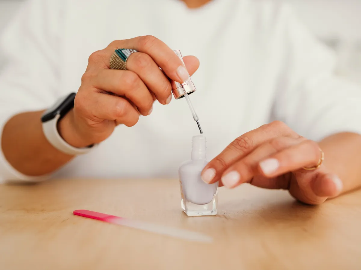 Pose de vernis sur une main, au salon